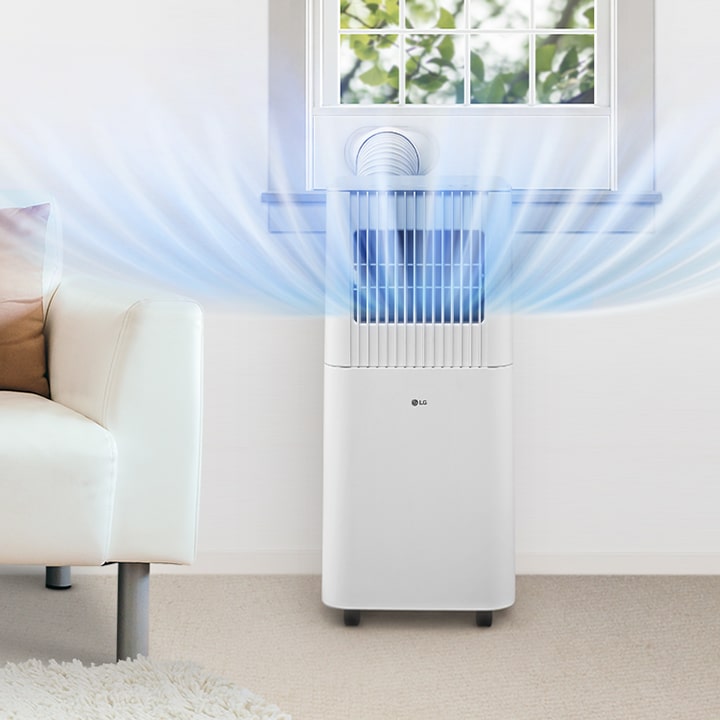 Aire acondicionado portátil LG que expulsa aire fresco ampliamente en una sala de estar, junto a un sofá blanco y una planta verde.