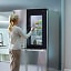 Mujer utilizando un refrigerador LG con panel de cristal InstaView, que permite ver rápidamente el interior sin abrir la puerta para ahorrar energía y mantener los alimentos más frescos.