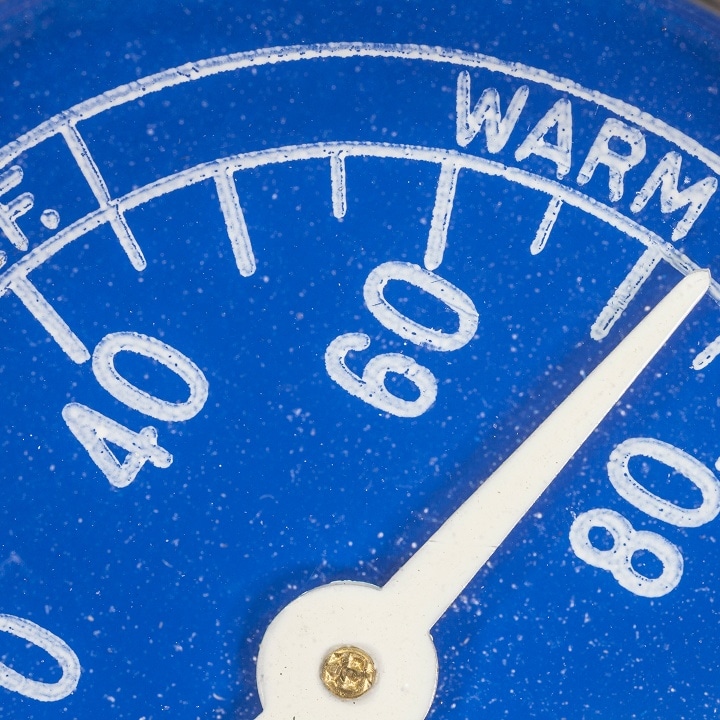 El termómetro de dial azul marca una temperatura cálida, lo que demuestra cómo los factores externos pueden afectar a la estabilidad de la temperatura interna del refrigerador y a la seguridad alimentaria.