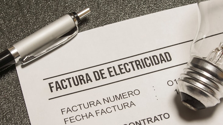 Primer plano de una factura de electricidad con un foco y un bolígrafo, que simboliza el aumento de los costos de electricidad cuando los refrigeradores se colocan junto a las cocinas de gas.