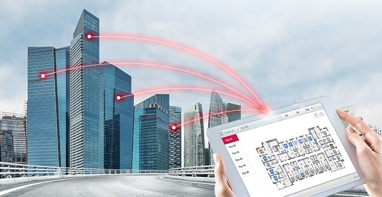 Una persona sostiene una tableta que muestra una solución de control. Cuatro líneas rojas se extienden desde la tableta y se conectan a edificios a la izquierda.