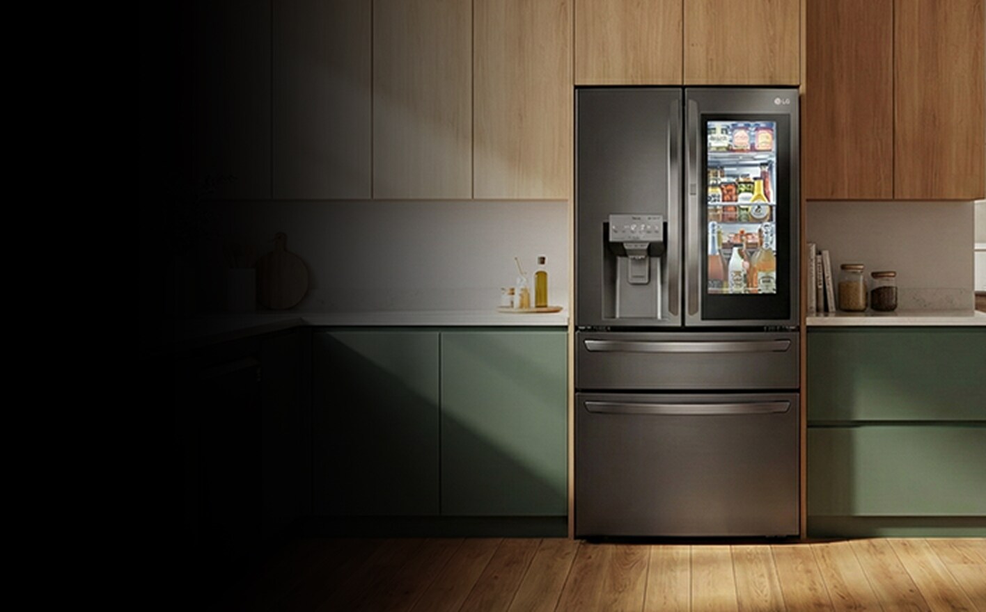 Un refrigerador de puertas francesas con puerta de panel transparente está colocado en una cocina luminosa, mostrando alimentos y bebidas ordenados en su interior.