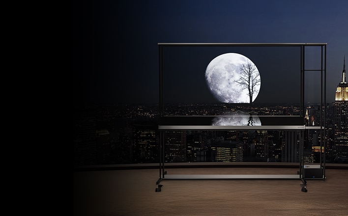 Televisor transparente en un balcón nocturno que muestra la luna llena y la silueta de un árbol con el horizonte urbano al fondo.