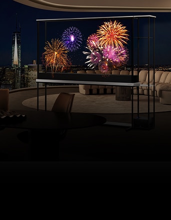 Televisor LG transparente que muestra fuegos artificiales vívidos en una sala de estar de lujo en un rascacielos durante la noche, con el horizonte de la ciudad visible al fondo.
