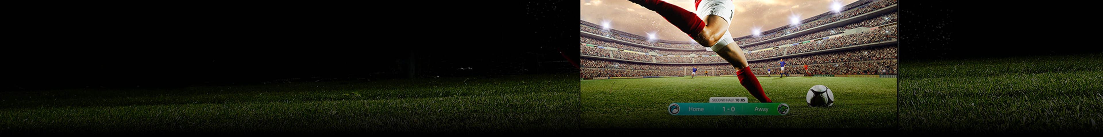 Imagen de un televisor LG OLED mostrando un partido de fútbol con un jugador con uniforme rojo a punto de patear el balón en el estadio. El marcador del juego es visible en la parte inferior de la pantalla. El césped verde del campo se extiende más allá de la pantalla hasta el fondo negro.