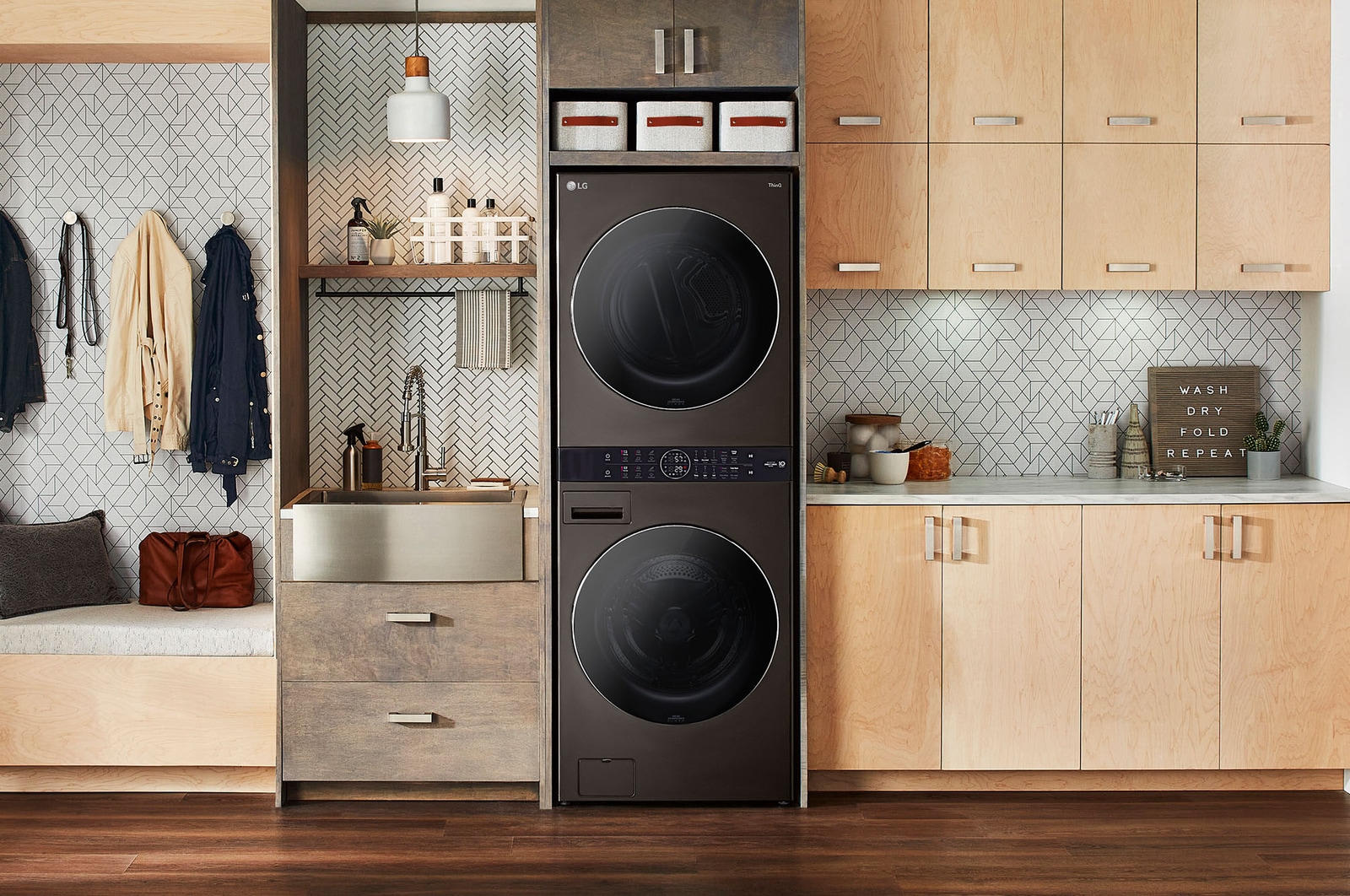 La LG WashTower® WK25BS6 en Black Steel (Lavadora 22 kg, Secadora 22 kg), instalada en un moderno cuarto de lavado con gabinetes de madera.