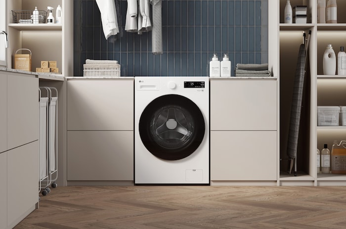 Lavadora de Carga Frontal LG WM16EWNTS6P Blanco Esencia, integrada en un moderno cuarto de lavado con gabinetes beige, fondo de azulejos azules y suelo de madera.
