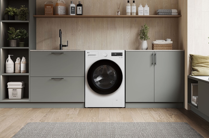 Lavadora de Carga Frontal LG WM20EWNTS6PGrafito Esencia, integrada en un moderno cuarto de lavado con gabinetes gris-beige y encimeras de madera.