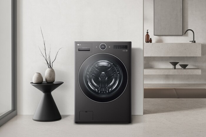 Lavasecadora LG WH25BFXS6B Negro Mate, integrada elegantemente en un baño o cuarto de lavado moderno y minimalista con paredes claras y acentos oscuros.