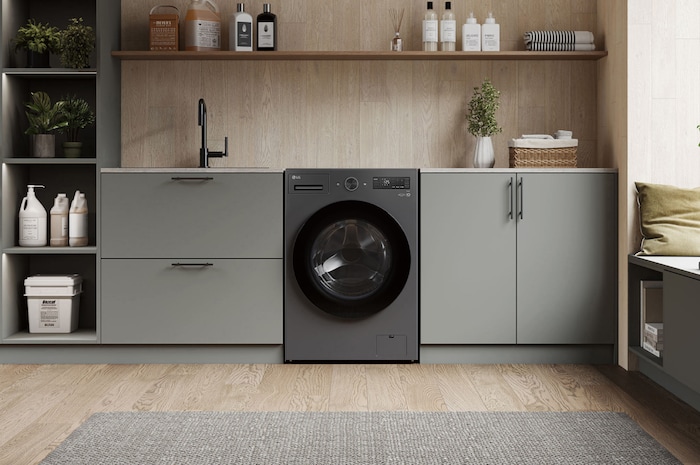 Lavadora de Carga Frontal LG WD20EGNTS6P Grafito Esencia, integrada en un moderno cuarto de lavado con gabinetes gris-beige y encimeras de madera.