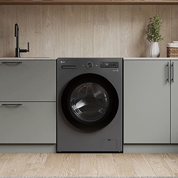 Lavadora de Carga Frontal LG WD20EGNTS6P Grafito Esencia, integrada en un moderno cuarto de lavado con gabinetes gris-beige y encimeras de madera.