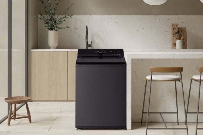 La lavadora de carga superior LG WT25PBTX6 de 25 kg en color Platinum Steel con panel de control negro, instalada en una moderna cocina o cuarto de lavado.