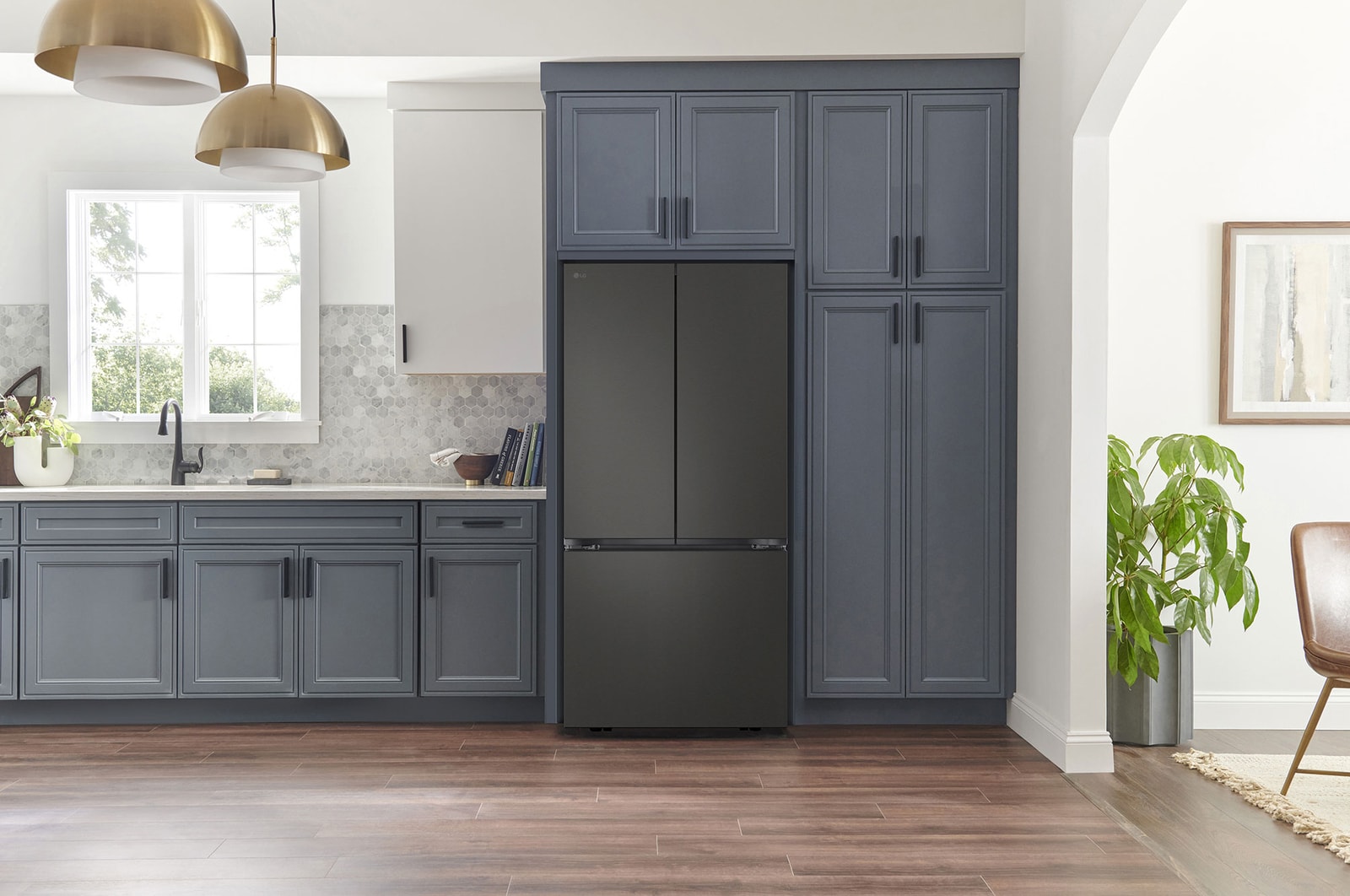 Refrigerador French Door LG GM25BPT Negro Mate, integrado en una cocina moderna con gabinetes azul marino, paredes blancas y lámparas colgantes doradas.