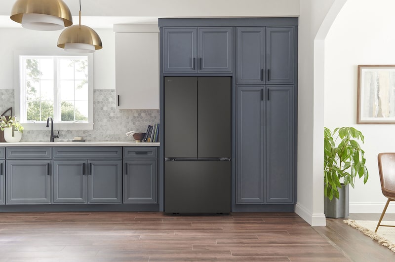Refrigerador French Door LG GM25BPT Negro Mate, integrado en una cocina moderna con gabinetes azul marino, paredes blancas y lámparas colgantes doradas.