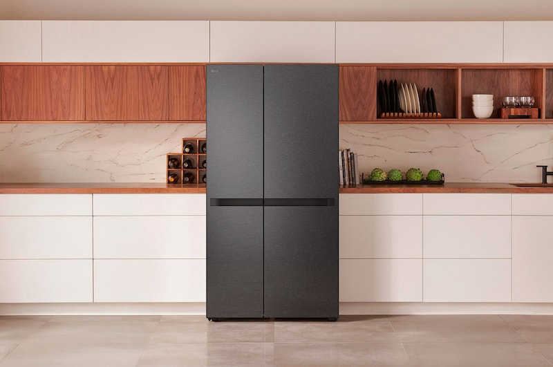 Refrigerador Side-by-Side LG VS23BEP con terminado acero negro mate, integrado en una cocina moderna con gabinetes blancos y de madera, con dispensador de agua externo.