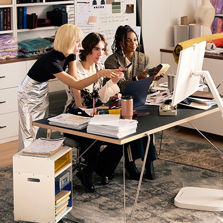 Monitor LG 32U889SA-W en acabado blanco en una oficina creativa moderna, utilizado para el trabajo en equipo colaborativo e integrado perfectamente en el espacio profesional.