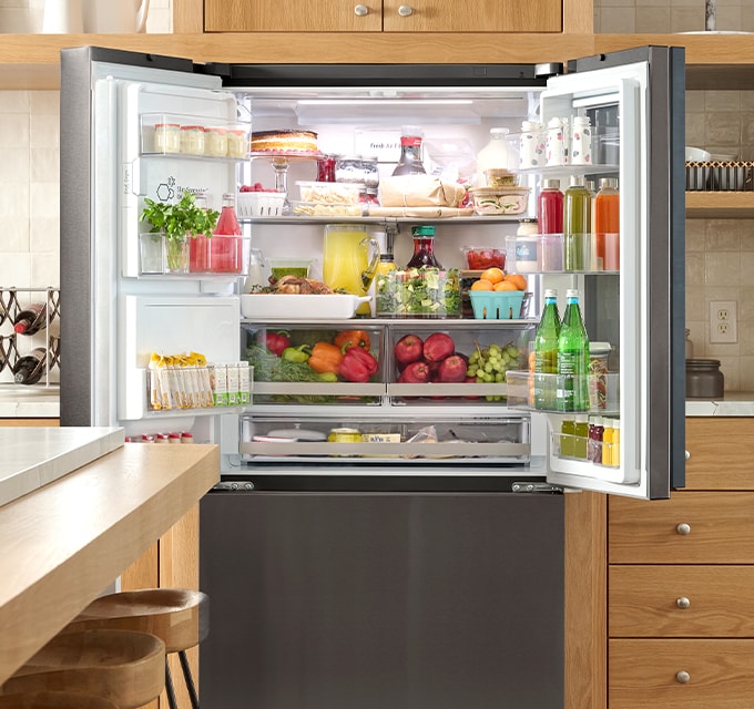 Vista interior totalmente abastecida del refrigerador LG, mostrando estantes organizados con frutas, verduras y bebidas.
