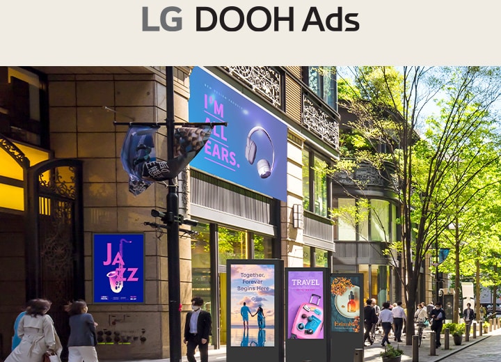 Esta imagen destaca la señalización digital en un espacio exterior, donde se muestran diversos anuncios sobre temas como música, viajes y belleza.