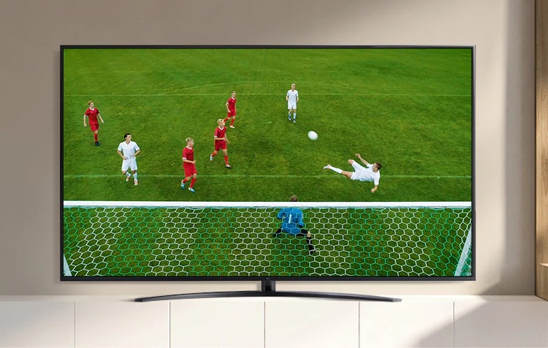 La pantalla de un televisor reproduce un video de un jugador de fútbol haciendo un gol durante un partido de fútbol. (reproducir el video)