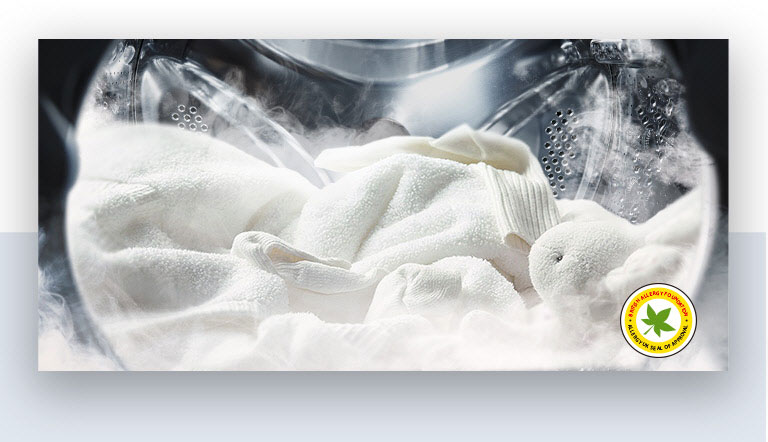 Un suave albornoz blanco y un peluche se muestran con vapor dentro del tambor de la lavadora.
