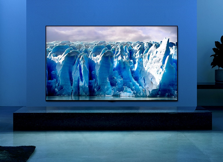 El video muestra un primer plano de la imagen del iceberg y hay un efecto visual del circuito azul sobre la imagen del iceberg. La escena cambia para mostrar un televisor colgado en la sala de estar con iluminación y fondo azules. Hay un gran iceberg en la pantalla del televisor.