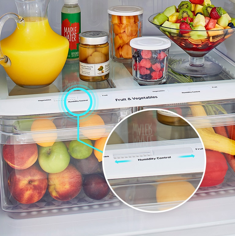 Los cajones inferiores del refrigerador se muestran llenos de productos. Un círculo ampliado muestra la palanca de control de humedad en la parte superior del cajón de cerca con flechas para indicar que se puede cambiar.