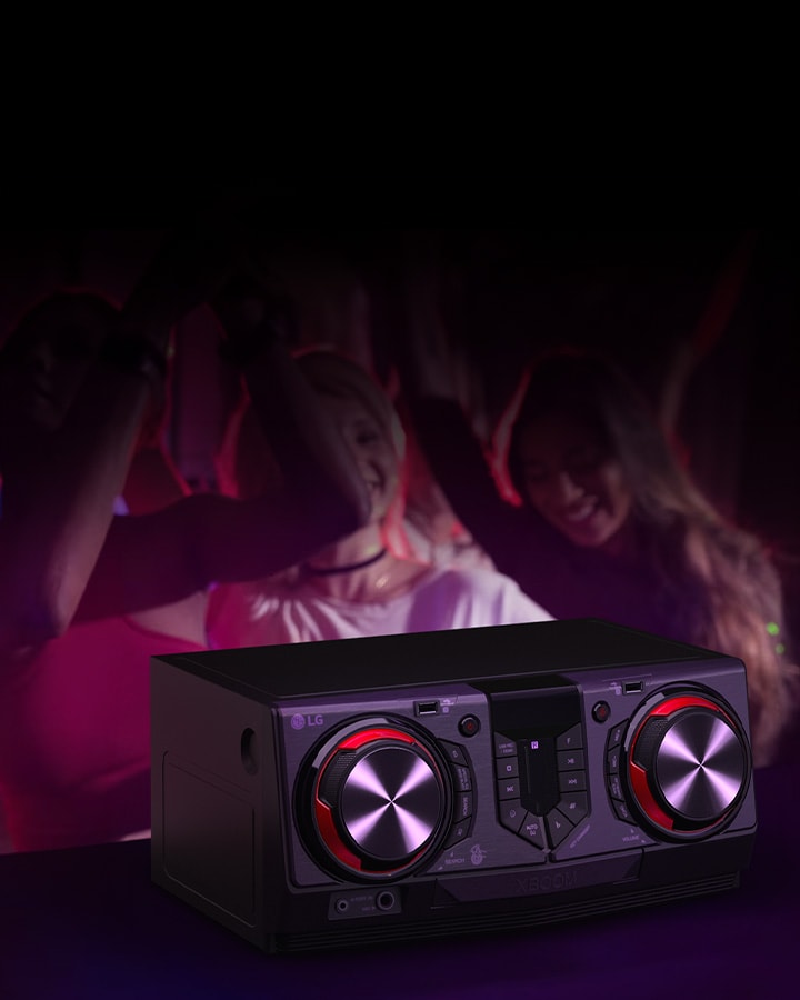 La imagen muestra un fondo difuminado que representa una escena de fiesta. Delante del fondo hay una mesa negra con un receptor colocado encima.