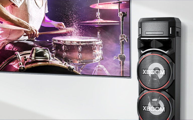 Un televisor está en una pared con un LG XBOOM a la derecha.