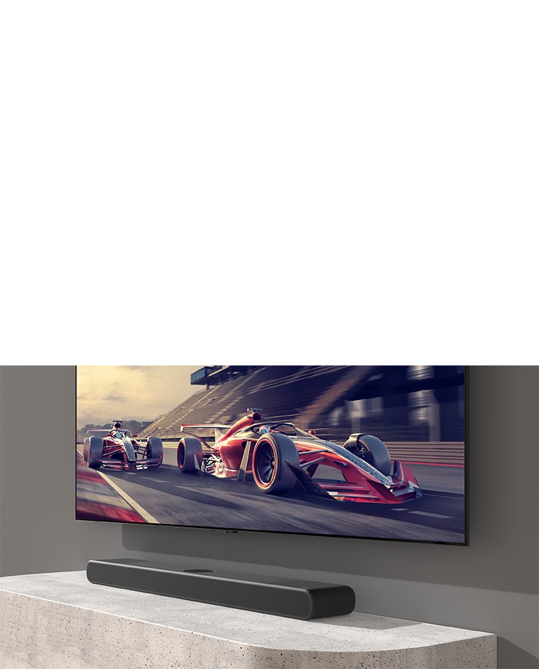La barra de sonido y el televisor se colocan sobre la mesa blanca y se muestra una escena de carreras en el televisor.