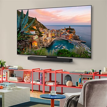Wide view of a stylish and colorful living room. LG OLED evo AI C5E 4K Smart TV is mounted on the wall with an LG Soundbar underneath it. The TV's design blends well with the space. On the TV screen is a colorful artwork. 