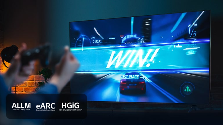 Un juego de carreras de coches en la línea de meta, con el cartel que dice "¡GANA!", mientras el jugador aprieta el joystick del juego. Los logotipos de ALLM, eARC y HGiG se encuentran en la esquina inferior izquierda.