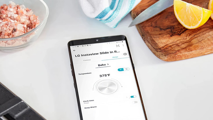 Un smartphone muestra la app LG ThinQ controlando el horno LG InstaView Slide-In Range, lo que permite un mantenimiento eficiente del producto en la cocina.