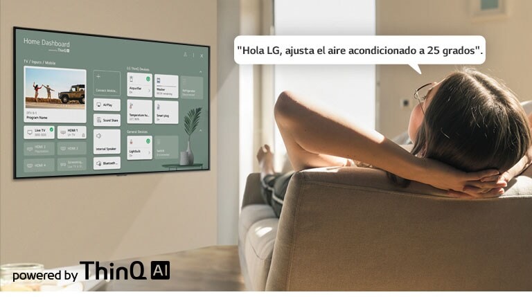 Mujer recostada en un sofá diciéndole a la TV que baje la temperatura con el Panel de inicio en la pantalla de la TV.