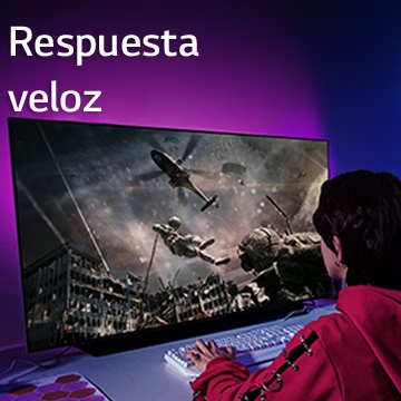 Una niña está jugando a un videojuego en una gran pantalla de un televisor que muestra a un soldado bajando de un helicóptero.
