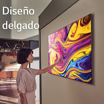 Una mujer está mirando un televisor colgado en la pared en el que se muestra una obra de arte.