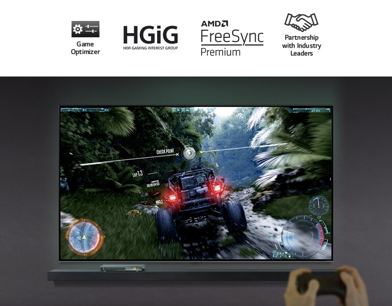 Un par de manos sosteniendo un controlador de juegos frente a un televisor. La pantalla muestra un automóvil andando por un camino de tierra que atraviesa un bosque.