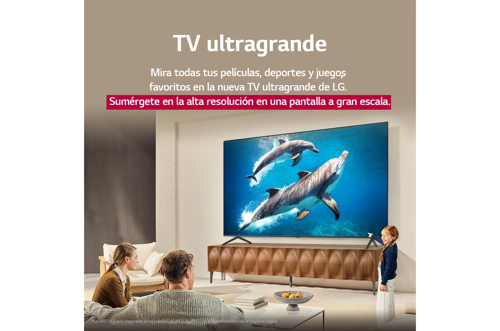 Una familia sentada en el sillón frente a una LG QNED TV situada sobre un soporte de televisión; una pequeña niña señala la pantalla que muestra dos delfines. El título habla de cómo puede disfrutar de la alta resolución en una pantalla gigante.