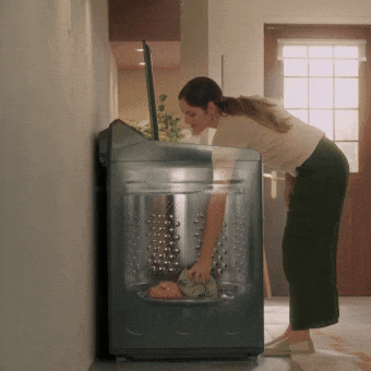 Mujer cargando y descargando ropa fácilmente en lavadora de carga superior