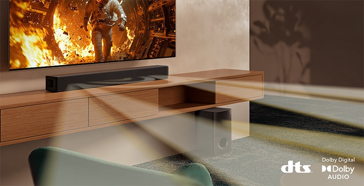 Se muestra un televisor con contenido científico y la barra de sonido SH5A se encuentra justo debajo. En el piso también se encuentra el subwoofer de la barra de sonido. De la barra de sonido y del subwoofer salen ondas sonoras blancas semitransparentes. En la parte inferior derecha se encuentran los logotipos de DTS y Dolby Digital Audio.