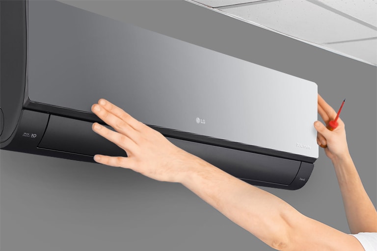 The side view of the air conditioner can be seen. Two hands are reaching up holding a tool, showing the ease of installation.