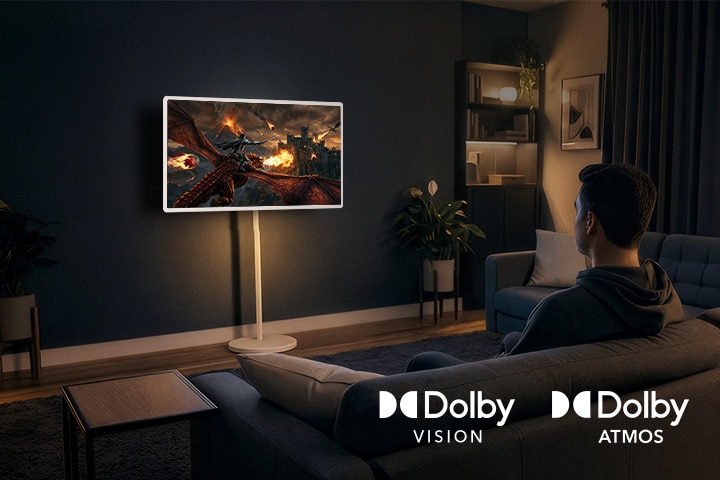 LG StanbyME 2 Max LX6 Bewegliche Leinwand mit Dolby Vision und Dolby Atmos zeigt einen Mann, der einen filmischen Drachenkampf in einem dunklen Raum beobachtet, wo lebensechte Bilder und immersiver Klang ein kinoähnliches Erlebnis zu Hause schaffen.