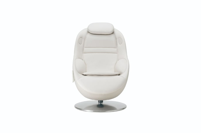 Straight‑on view of white massage chair on a round metal base against a plain neutral backdrop.