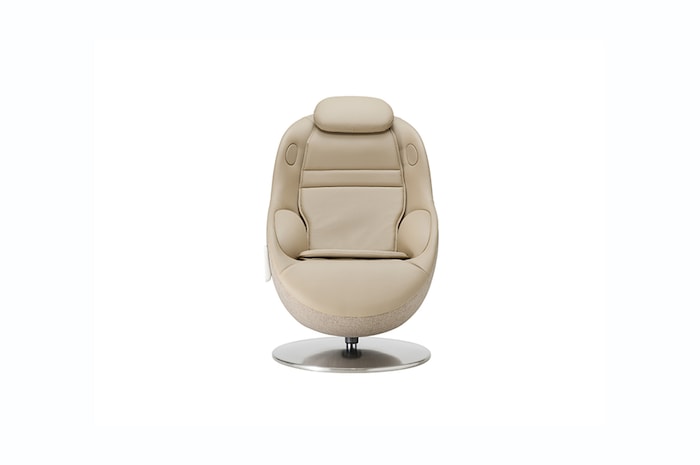 Straight‑on view of white massage chair on a round metal base against a plain neutral backdrop.