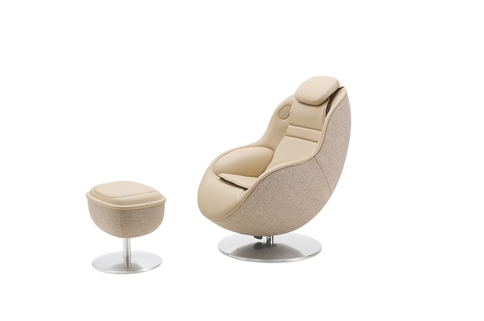 White massage chair with matching round footstool on a metal pedestal against a light background.