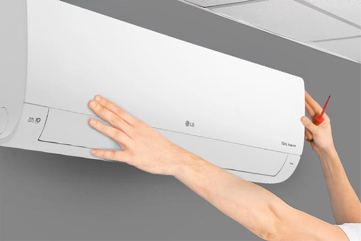 The side view of the air conditioner can be seen. Two hands are reaching up holding a tool, showing the ease of installation.