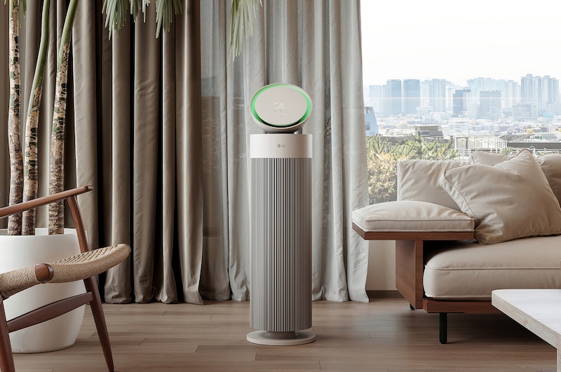 LG air purifier placed in a stylish living room with a beige sofa, dark bookshelf, and modern décor