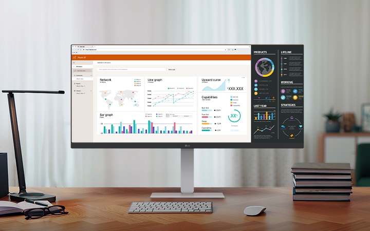 A modern home office setup featuring a large ultra-wide LG monitor displaying data dashboards and graphs, with a wireless keyboard and mouse on a wooden desk.