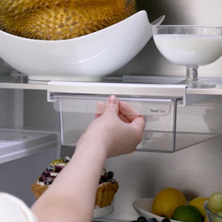 The fresh tray feature of an lg french door refrigerator demonstrates its use by hanging below shelves, placing on top of shelves, or setting inside drawers.
