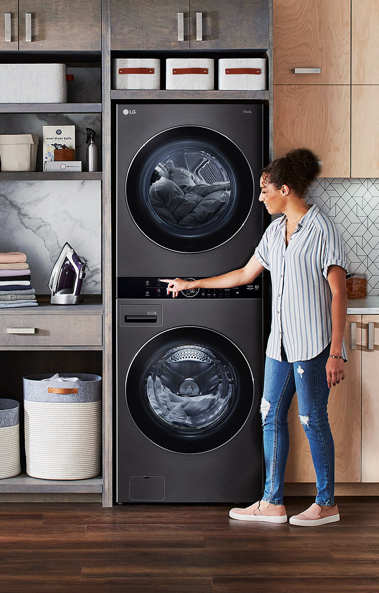 A black LG Wash Tower is installed with shelving and a closet in a wall unit.