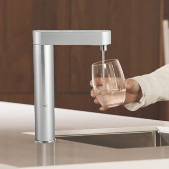 Pouring water from the purifier into a cup on the sink	